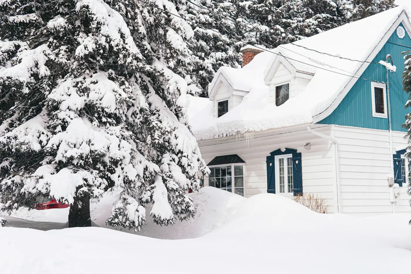 Maison au toit chargé de neige après une tempête